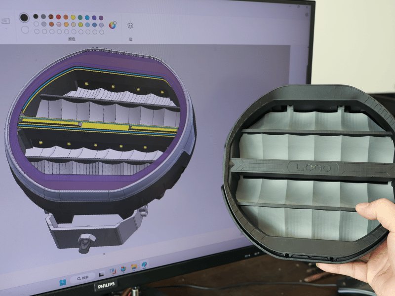 Engineer holding a 3D-printed LED work light housing prototype next to its CAD model