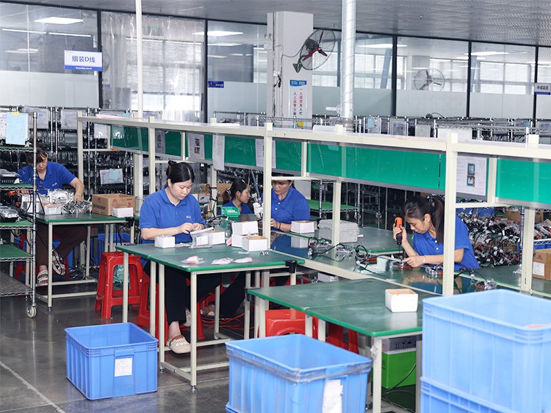Technicians assembling LED work lights at organized stations in the workshop