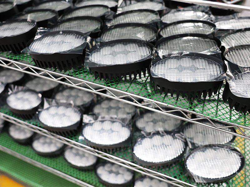 Semi-assembled LED light modules with optical lenses and finned heat sinks on racks