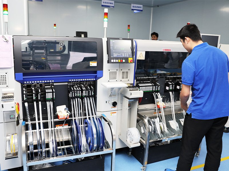 An operator at a Yamaha SMT pick-and-place machine mounting LED board components